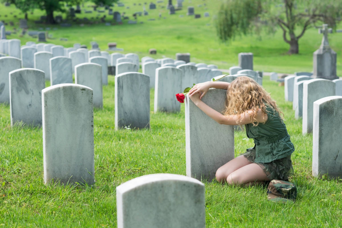 Woman leaning at graveyard on grave stone